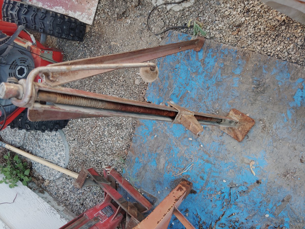 Rusty metal jack with worn handle standing outside